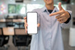 © bongkarn - Close up of man holding and pointing at white screen smartphone while standing in cafe or classroom