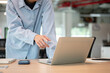 © bongkarn - Close up of a man's hand pointing at laptop screen while standing leaning over wooden table in cafe.