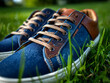 © Rakib - Close up of stylish denim sneakers with brown leather accents resting on green grass