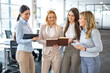 © Bojan - Four businesswomen in office discussing data from notebooks, making decisions for company success
