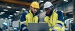 © MP Studio - The engineers reviewing laptop data while inspecting industrial machinery in a busy factory