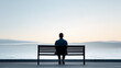 © GrayFrog - Rear view on a man sits alone on a bench with a view on sea - loneliness and mental health problems.