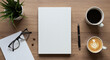 © Yoga - Top view of a modern wooden office desk with a blank white journal for copy space, two cups of coffee, and essentials for work