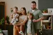 © AnnaStills - Caucasian middle aged woman standing with man, smiling while holding boy with stuffed animal, older boy standing in front