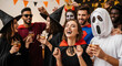 © Ksenia Pestereva - Halloween party with friends enjoying a Halloween party, dressed in costumes. Halloween party atmosphere with costumes, drinks, and happy people, celebrating with friends.