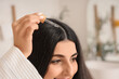 © Pixel-Shot - Young brunette woman applying serum for hair growth in bathroom, closeup