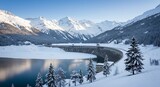 Majestic winter landscape featuring a large concrete dam across a partially frozen lake, surrounded by towering snow-capped mountains and pristine pine forests under a clear blu...