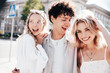 © halayalex - Young three stylish friends posing in the street. Fashion man and two cute female dressed in casual summer clothes. Smiling models having fun. Cheerful women and guy outdoors, in sunny day