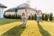 © Maria Vitkovska - Happy family running in garden of sustainable home with solar panels