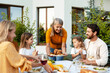 © Maria Vitkovska - Beautiful grandmother serving roasted chicken to family at garden, festive dinner