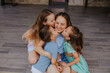 © Westend61 - Mother enjoying affectionate hugs and kisses from children outdoors