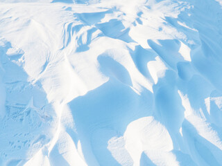 Wall Mural - Snow texture. Wind sculpted patterns on snow surface. Wind in the tundra and in the mountains on the surface of the snow sculpts patterns and ridges (sastrugi). Arctic, Polar region. Winter background