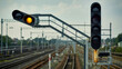© Creativeraf - Modern railway signals with yellow and red lights illuminated on a cloudy day