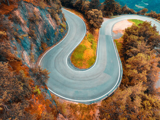 Wall Mural - Aerial view of mountain curvy road and red forest in autumn. Dolomites, Italy. Top view of winding road on mountain pass, orange trees in fall. Road in the woods. Colorful landscape with road in Alps
