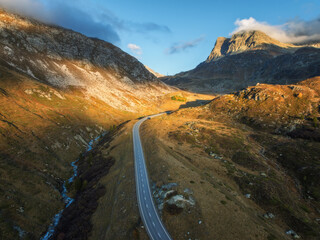 Wall Mural - aerial view of winding road in high alpine valley in the swiss alps, switzerland in autumn at sunset