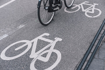 Close view of cycling lane with painted white bicycle icons in Copenhagen, perspective showing infrastructure for sustainable mobility and modern European urban lifestyle