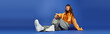 © Bliss - Fashionable young woman poses stylishly against a vibrant blue backdrop with a confident attitude