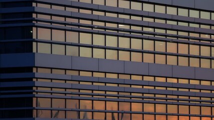 Wall Mural - Modern office building reflecting orange sunset light in glass windows