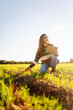 © maxbelchenko - Young female farmer with digital tablet in green agricultural field in sun. Female agronomist in field with green sprouts checks the growth and quality of the crop. Farming and technology concept.