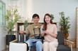 © Natee Meepian - Travel Enthusiasts. Young couple smiling together with luggage and camera at home.