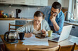 © Geber86 - Young couple going over their bills at home in the kitchen