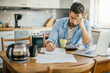 © Geber86 - Young man going over his home finances in the kitchen