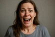 © Татьяна Евдокимова - Surprised woman screaming with laughter, showcasing an authentic expression of joy and excitement against a simple grey background