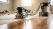 © DigitalSpace - Orbital sander in motion across hardwood floor with dust extraction system attached highlighting clean and ecoconscious refinishing procedures during remodeling.