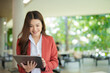 © maeching - Asian businesswoman standing in front of modern business building and using tablet to work.
