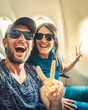 © Evaldas - Happy casual dressed tourist taking selfie inside airplane - Cheerful couple on summer vacation - Passengers boarding on plane - Holidays and transportation concept