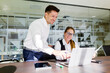 © muse studio - Colleagues discussing project details in modern office setting while working on laptop and sharing ideas