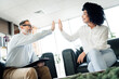 © deagreez - Business professionals exchange a high five in a modern office space, symbolizing teamwork, partnership