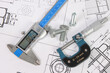 © bayurov - Micrometer, caliper and hardware on a background of engineering drawings.
