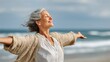 © Johannes - happy mature woman with arms outstretched feeling the breeze at beach beautiful middle aged woman with arms up dancing on beach mid lady feeling good and enjoying freedom at sea copy space no logos n