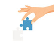 © Nidia - A hand carefully places a blue jigsaw puzzle piece into its matching white counterpart.