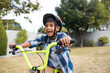 © wavebreak3 - Excited boy riding bicycle in backyard, wearing helmet and enjoying outdoor fun, copy space