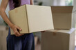 © STBSTD - Adult Asian woman transports moving box to new home apartment preparing for relocation organization