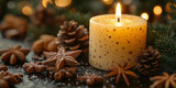 Płonąca świeca w otoczeniu świątecznych dekoracji, w tym szyszek, anyżu gwiazdkowego i pierniczków. Ciepła, bożonarodzeniowa kompozycja.