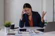 © David - Business asian woman with head in hand at desk in office