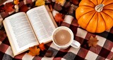 Cozy autumn arrangement with hot chocolate mug, book, and pumpkin on plaid blanket