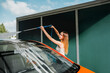 © ADDICTIVE STOCK - Woman washing car using high-pressure water