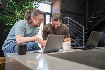 two laughing it software engineers working on project and programming in coffee shop. successful sta