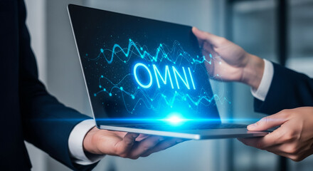 Digital OMNI: A close-up captures the passing of a sleek laptop between hands, its screen illuminated with the word OMNI, accompanied by glowing data patterns.
