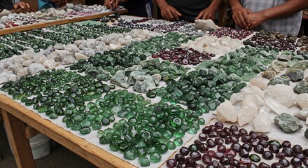 A table displays various cut and raw gemstones Hands and arms are partially visible