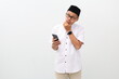 © ArvStd - Portrait of a thinking dreaming asian muslim man posing isolated over white background using mobile phone