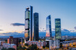 © Andrés García - Cityscape of Madrid’s financial district at dusk, featuring modern skyscrapers illuminated against the fading evening sky.