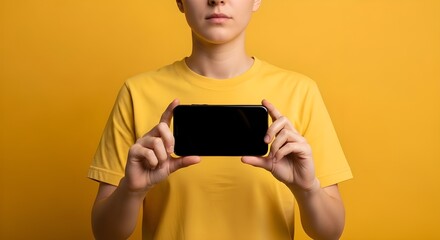 Person in yellow t shirt holding a black smartphone with blank screen