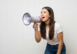 © Kamat - Excited young woman with megaphone announcing important news with vibrant energy