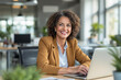 © JD Images - smiling businesswoman sitting at her desk in front of her computer