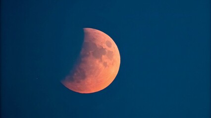 Wall Mural - This image is a mesmerizing photograph or artistic rendering of a lunar eclipse. It features the moon in its full phase, but with a portion of it darkened by the Earth's shadow.